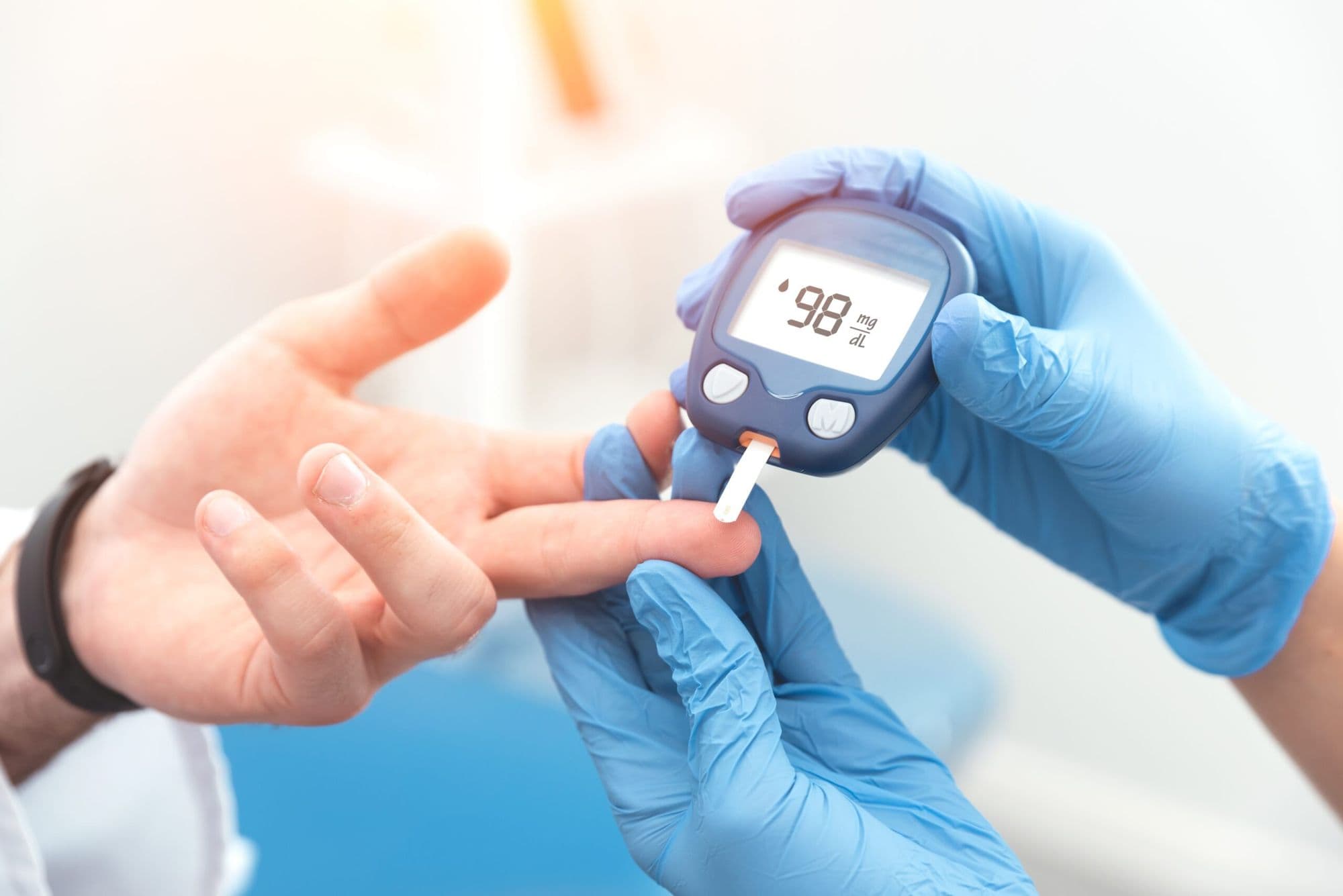 A glucose meter reading a fingertip sample